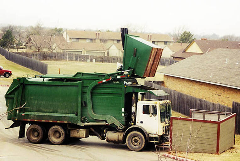Dumpster being picked up and emptied in a housing development in Norwalk, CT.